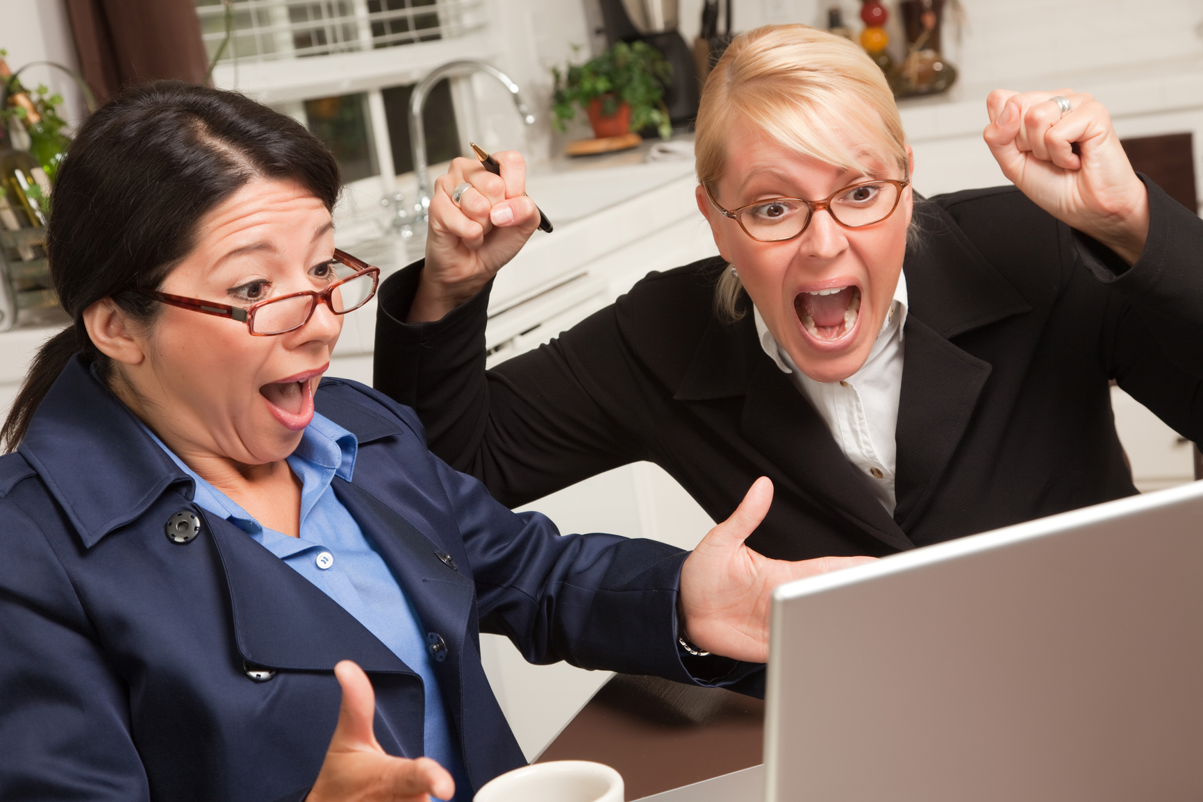 Businesswomen Celebrate Success on the Laptop in the Kitchen.